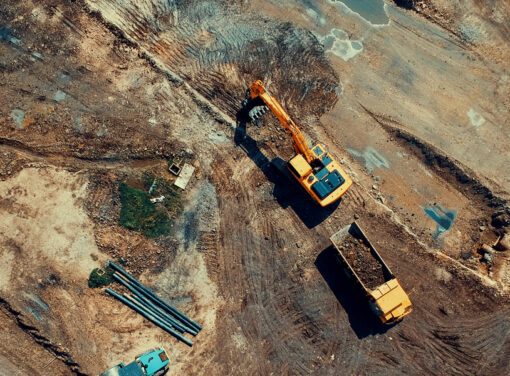 Construction site covered by raw earth and heavy machinery moving dirt around