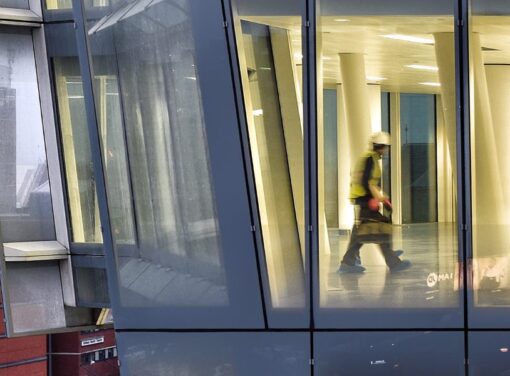 View of office building under construction with motion blur of construction worker walking inside