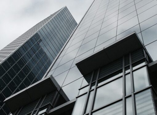 Modern office building with all glass exterior and cloudy sky in background