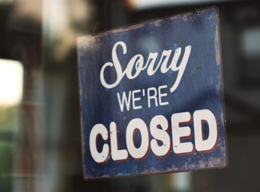 Sign in front glass of building that reads "Sorry We're Closed"