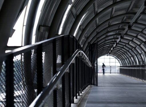 Business person at end of transportation atrium with view of handrail