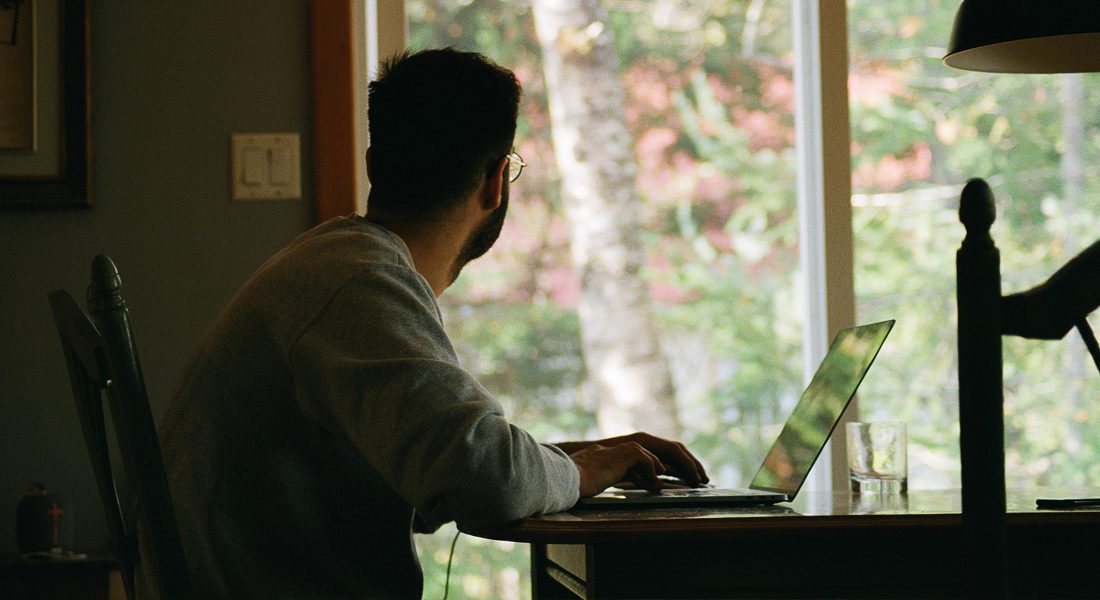 Business employee working from home at kitchen table looking out window