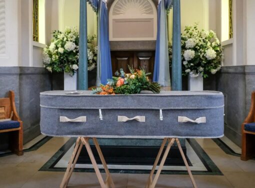 Casket on stand in funeral home surrounded by flowers