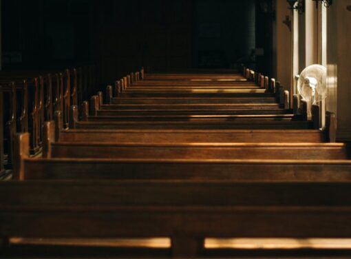 Inside of church viewing the back of a row of pews