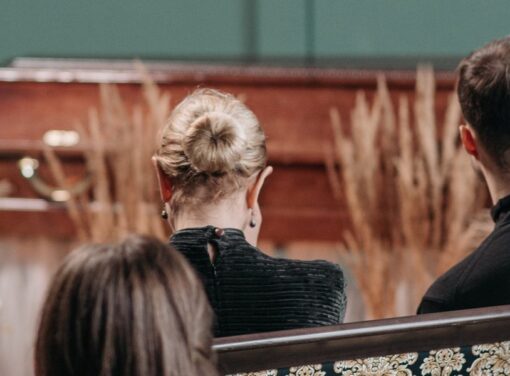 Family members dressed in black at funeral sitting down looking at cascket