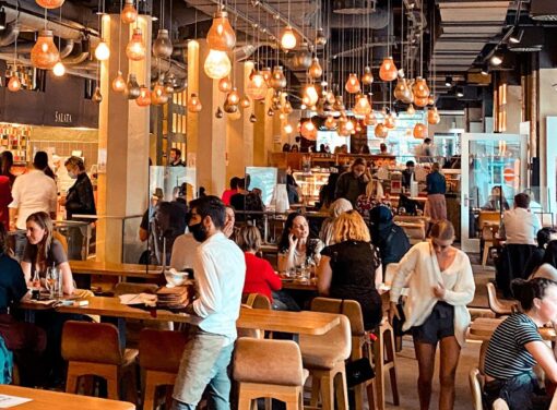Modern restaurant filled with large group of people, some with COVID masks on