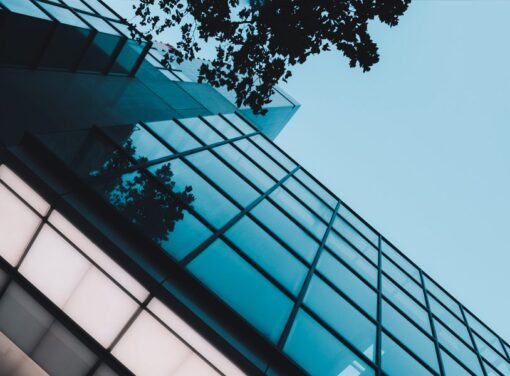 Facade of modern office building with glass windows and blue sky in background