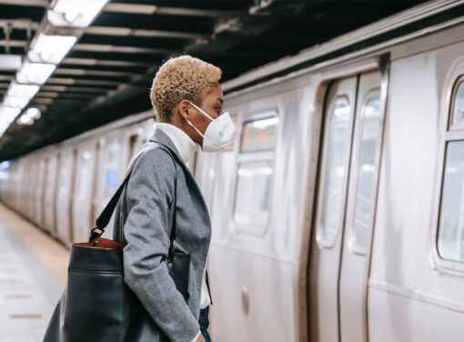 African American business woman walking onto subway with COVID mask on