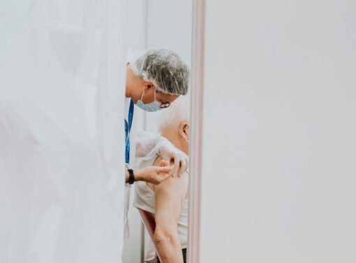 Senior Care facility nurse administering a vaccine to an ederly gentleman