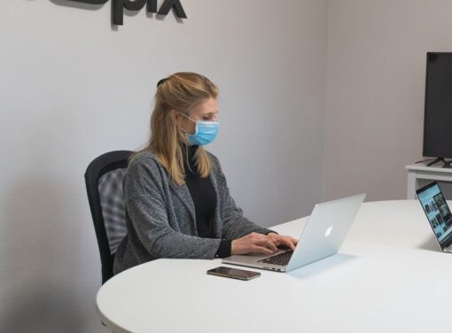 Female business professional working in office at desk with COVID mask on
