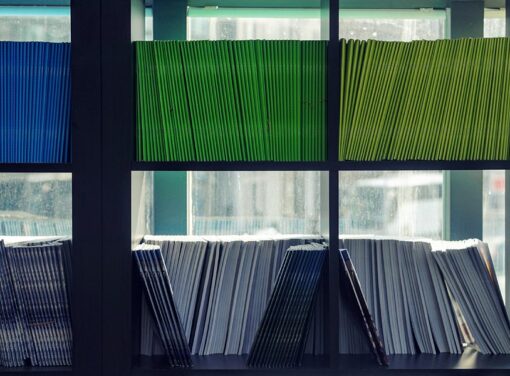 Image of a shelving unit containing books and other resources that's next to a building window