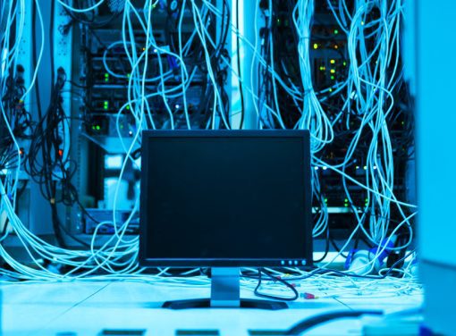 Computer with server hardware behind it in blue shaded room