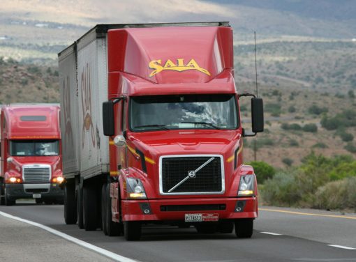 Two large commercial trucks driving on highway