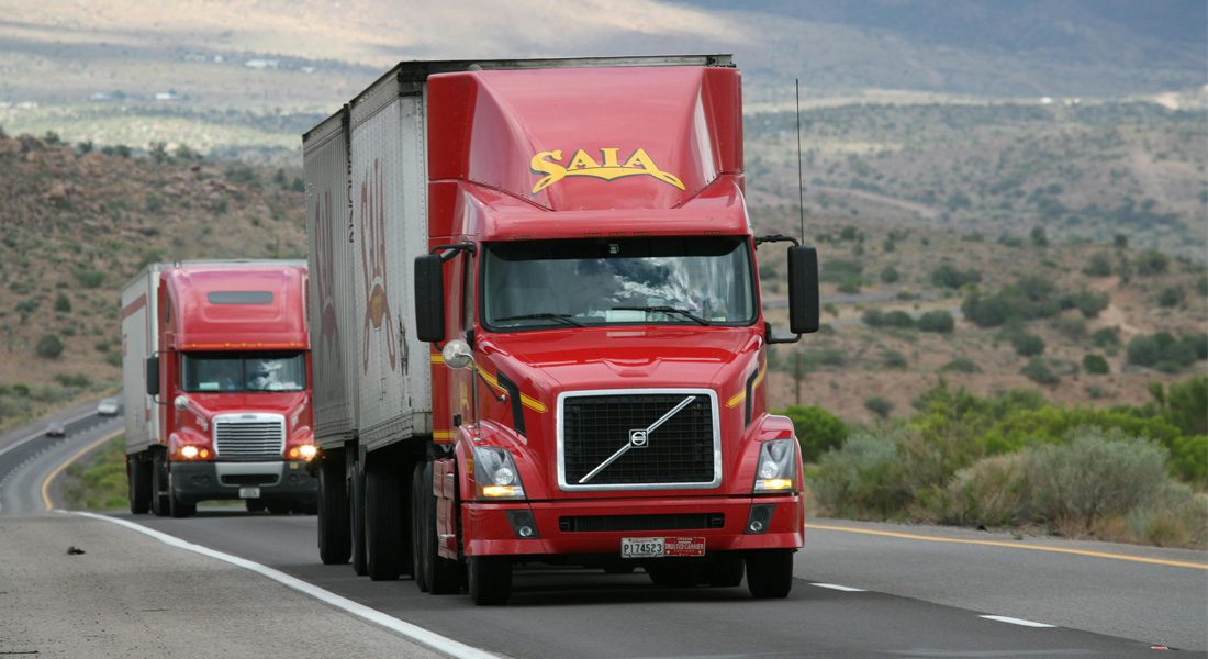 Two large commercial trucks driving on highway