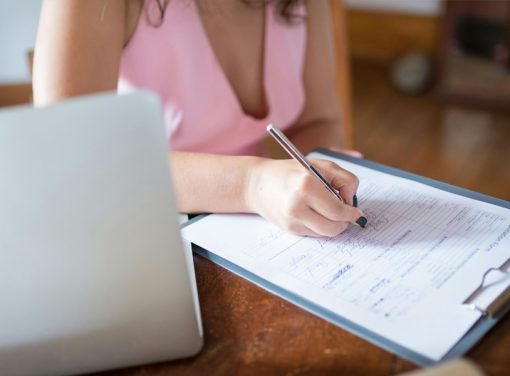 Girl signing paper on desk next to computer