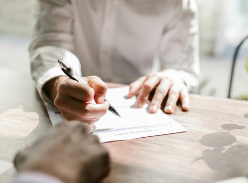 person signing paper at desk in front of boss