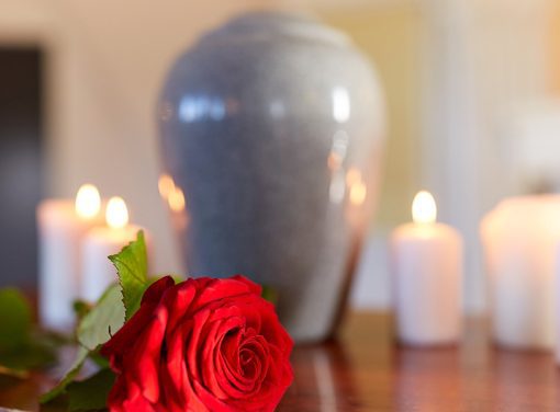 Funerary urn surrounded by candles and a rose