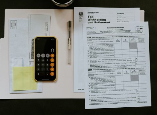 Tax paperwork and phone calculator in open folder on desk