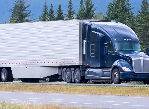 freight truck driving down wooded highway