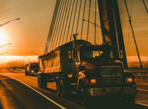 Semi-Truck driving across bridge during sunset