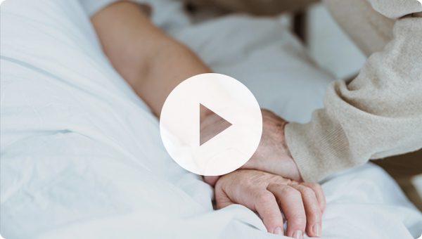 Family member holding hands with someone in hospital bed