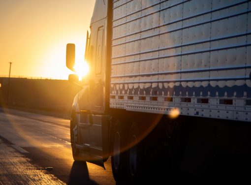 Semi truck driving down highway at sunset