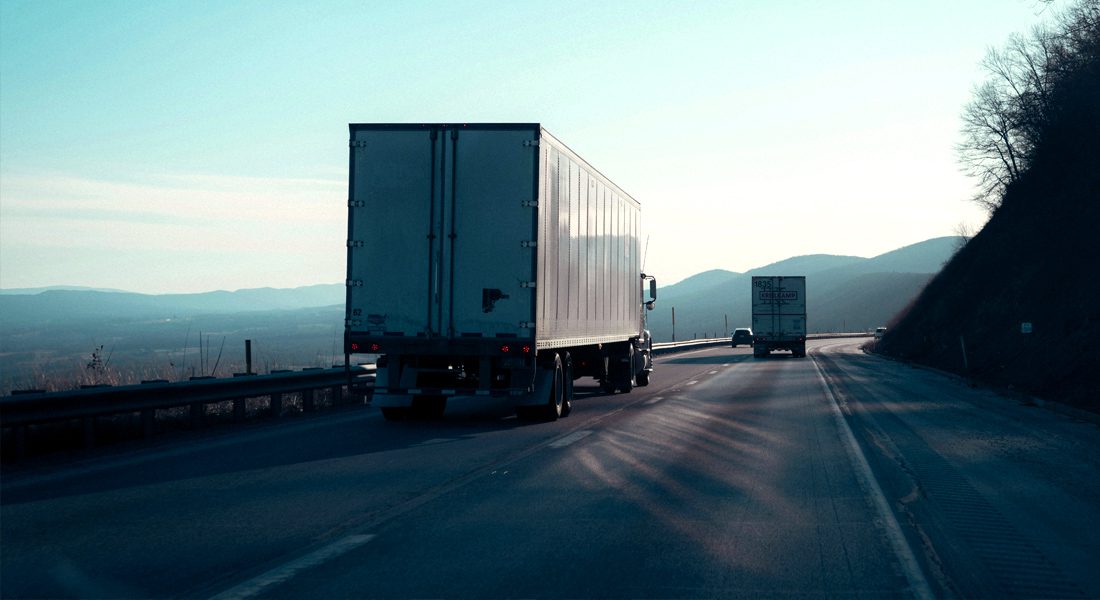 Semi truck driving down highway with valley in background