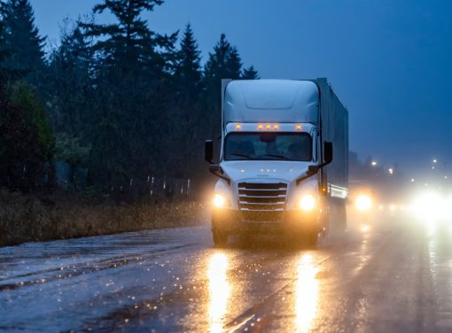 Semi truck driving down road on dark stormy night
