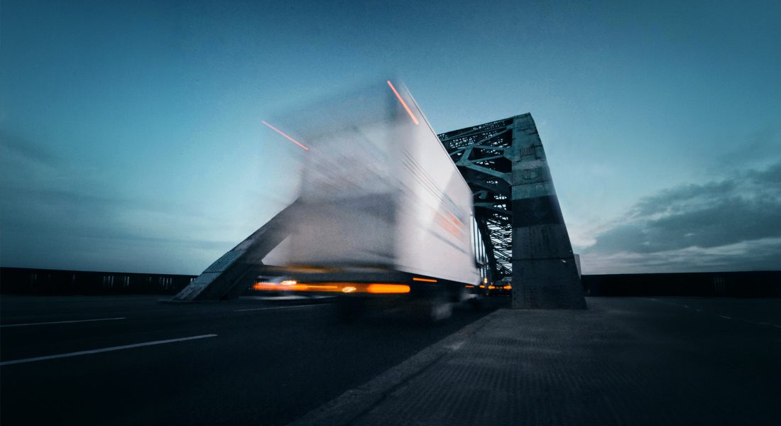 Semi truck driving over bridge at dusk