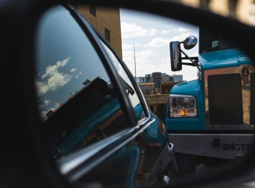 Rear-view mirror of car with close up of semi-truck in sight